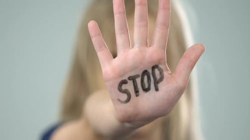 Verängstigtes junges Mädchen zeigt Stoppschild, Opfer häuslicher Gewalt, Missbrauchsbewusstsein