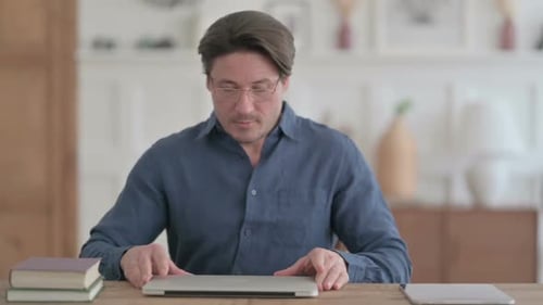 Young Man Coming Back Opening Laptop in Office