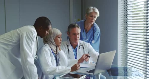 Front view of Multi-ethnic doctors discussing over laptop in hospital