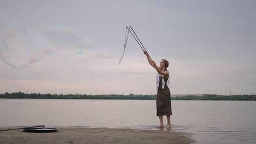 Woman Creates Large Soap Bubbles on Beach