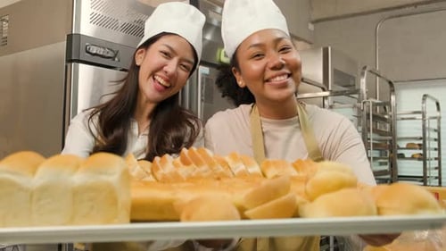 Smiling bakers presenting a tray of fresh bread