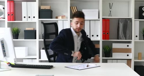 Junger erwachsener Geschäftsmann kommt an seinen Arbeitsplatz in einem modernen Büro