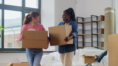 Two Young Women Moving Boxes into New Home