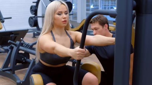 Woman Works Out on Machine at Gym
