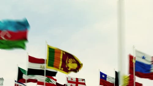 International Flags Waving in Wind Against Cloudy Sky