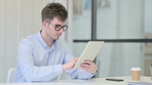 Attractive Young Man Using Tablet in Office