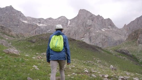 Hiker with Backpack Walking Toward Mountains