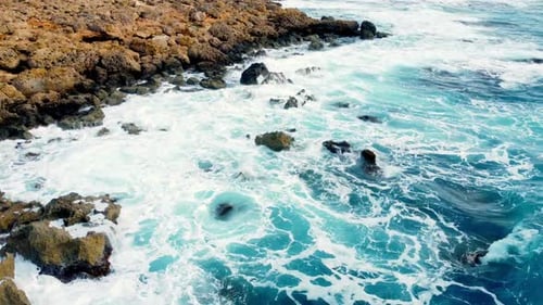 Sea Waves Washes the Rocky Shore Above Aerial Shot Flying Over Coastline Cliffside with Blue Pure