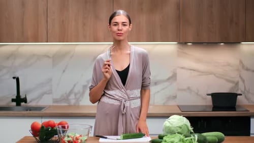 Woman Tastes Salad Ingredients in Modern Kitchen