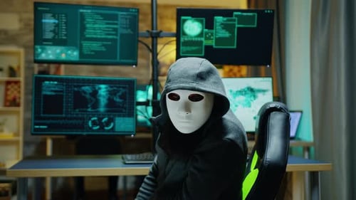 Masked Hacker Sits Before Multiple Monitors
