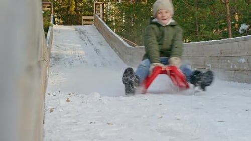 Happy Boy Rodeln auf Rutsche im Winter