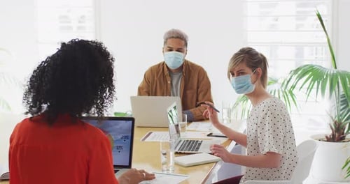 Office colleagues wearing face masks discussing in meeting room at office