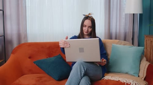 Woman Sits on Couch with Laptop