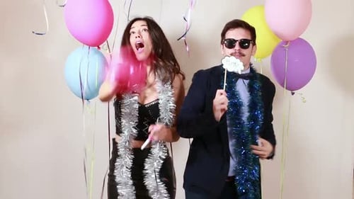 Crazy couple dancing and blowing party horns