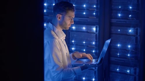 Man Using Laptop in a Blue Lit Data Center