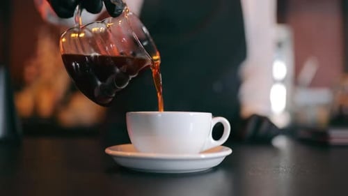 Coffee Pouring into Mug in Cafe Setting