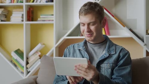 Smiling Man Using Tablet Relaxing on Sofa in Modern office.Concept of Young Business People Working