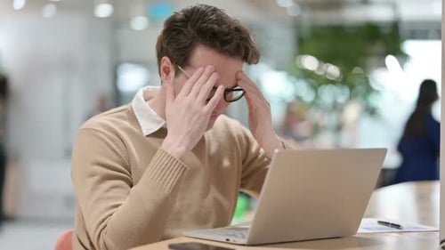 Stressed Young Adult Man Working on Laptop in Office