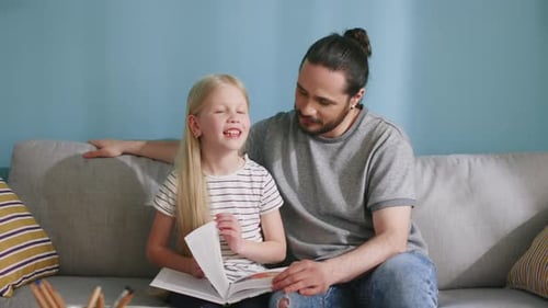 Father and Daughter Reading Together on the Couch