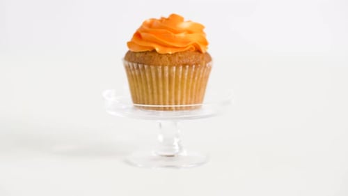 Cupcake with Orange Frosting on Glass Stand
