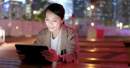 Woman Using Tablet Device Outdoors at Night