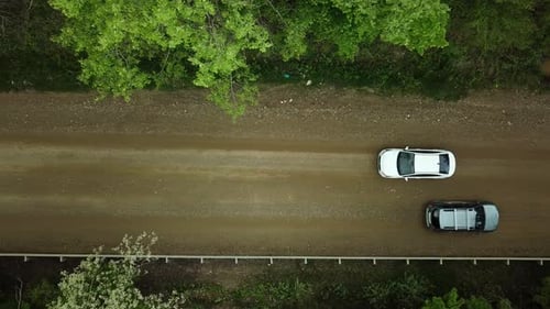 Aerial Top Down View of White Car Driving on Rural Road in Forest
