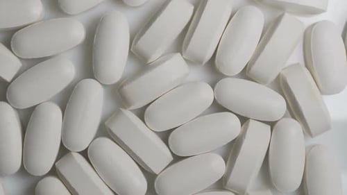 El
primer plano de las cápsulas blancas gira sobre la mesa. Pastillas antibióticas de farmacia