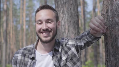 Portrait of Handsome Young Man in the Pine Forest, Looking in the Camera and Smiling Close-up. Unity