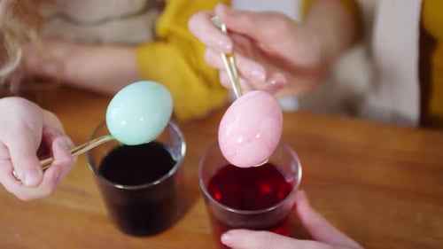 Hands Holding Dyed Easter Eggs on Spoons