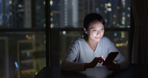 Woman Uses Smartphone in Urban Apartment at Night
