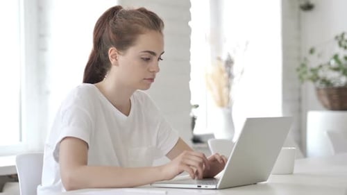 Young Woman Using Laptop at Desk Reacts to Surprise