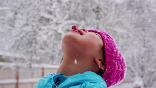Child Catches Snowflakes on Tongue in Winter