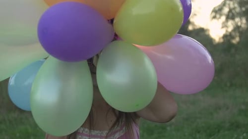 Happy Girl with Balloons in a Golden Field