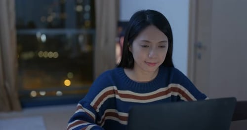 Woman Works on Laptop at Home at Night