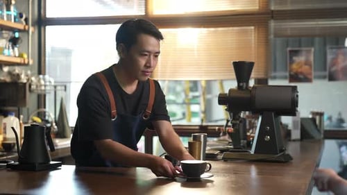 Smiling Barista Serving Coffee at a Cafe Counter