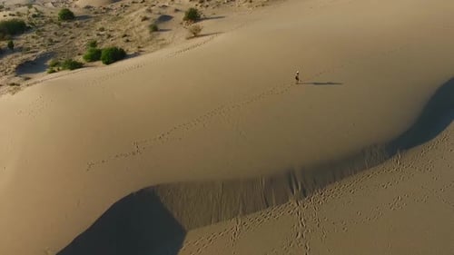 Woman Walks Across Expansive Desert Sand Dunes