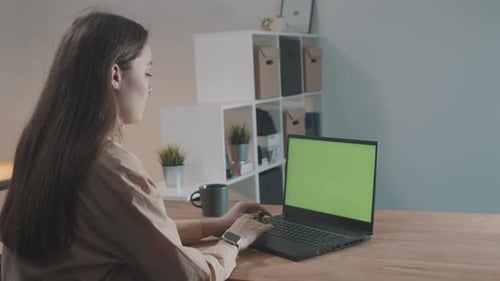 Girl in a Modern Office Working on a Laptop with Green Screen