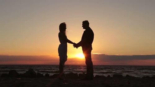 Couple heureux main dans la main sur la plage au coucher du soleil