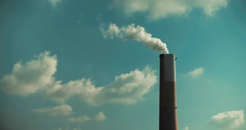Time lapse of a smoke coming out of a power plant chimney, clouds and blue sky