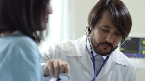 Doctor Uses Stethoscope on Patient in Hospital