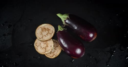 Fresh Eggplant and Slices on Black Surface