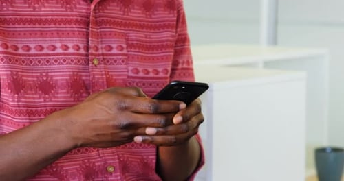 Mittelteil eines männlichen Grafikdesigners mit Handy im Büro 4k