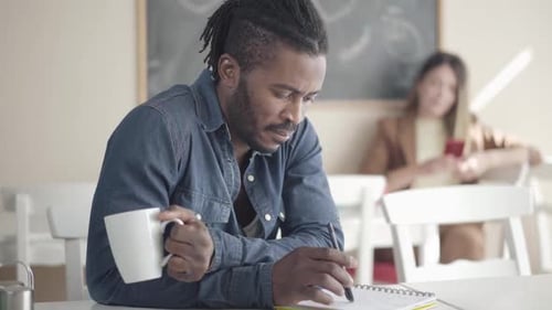 Man Writing with Mug Indoors with Woman