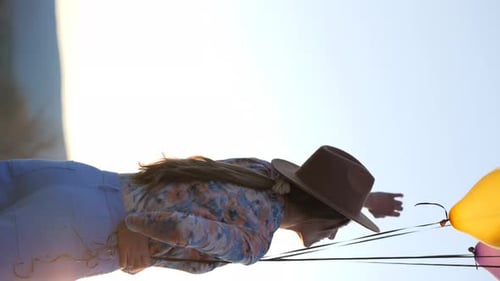 Positive woman dancing with balloons near lake
