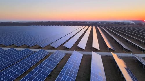 Drohnenansicht großer Sonnenkollektoren auf einem Solarpark bei strahlendem Sonnenuntergang im frühen Winter