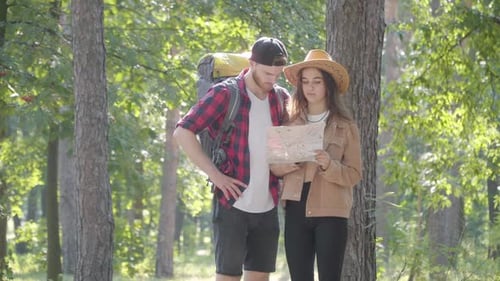 Couple Looks at Map and Hikes in Forest
