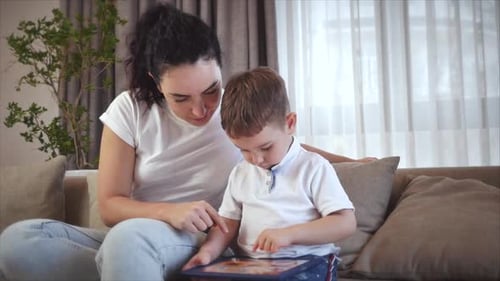 Woman and Child Interact With Tablet on Sofa