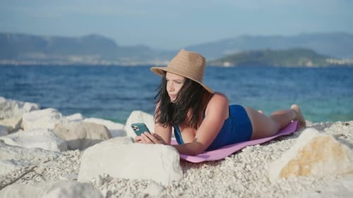 Woman Sunbathes on the Beach and Writes on the Phone