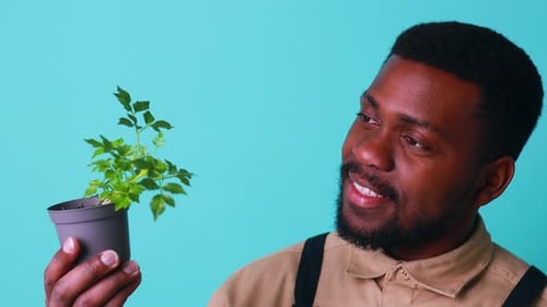 Young Adult Holding Small Potted Plant, Smiling