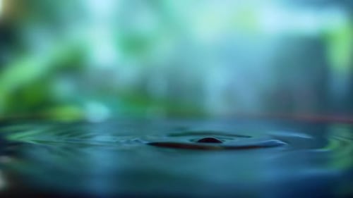 Close up. It is raining outside. Raindrops break into a puddle. water drop on nature background.